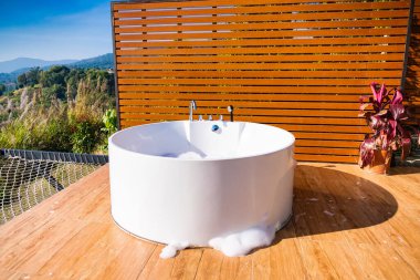 Phetchabun, Tayland - Ocak, 06, 2025: Zarif ahşap güvertede Beyaz Küvet ile Açık Hava Banyo İnzivası Phetchabun, Tayland.