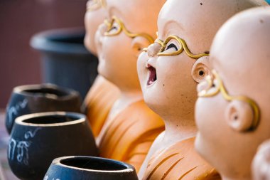 Lop Buri, Tayland - Ocak 02, 2025: Turuncu cüppeli renkli keşiş heykelleri Tayland 'ın Lop Buri kentinde gün ışığında taştan bir yüzeyde sergilenen bağış kaseleri