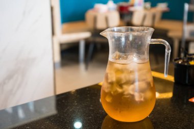 Buzlu çayla dolu şeffaf bir cam sürahi bir restoranda granit tezgahta durur.