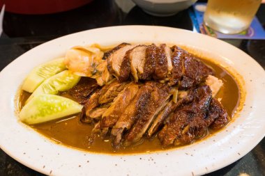 Yakın plan kızarmış ördek, çıtır çıtır deri ve sulu et restoranda beyaz bir tabakta servis edilir..