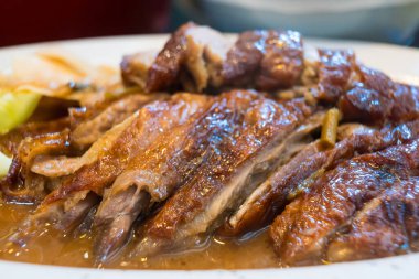 Yakın plan kızarmış ördek, çıtır çıtır deri ve sulu et restoranda beyaz bir tabakta servis edilir..