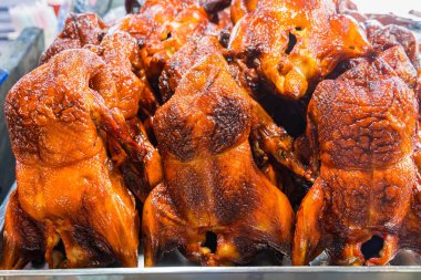 Bir sıra kızarmış tavuk ve çıtır çıtır altın sarısı derisi bir markette sergileniyor.