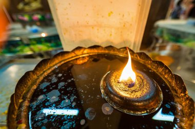 Parlayan bir gaz lambasının, renkli bir ortamda parlak bir alevle yakın çekimi, sıcaklığı ve manevi ortamı çağrıştırıyor..