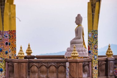 Phetchabun, Tayland - Ocak 06, 2025: Huzurlu bir Buda heykeli, Tayland 'ın Phetchabun kentindeki sakin bir gökyüzü altında, dekore edilmiş bir platformda meditasyon yapıyor..