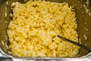 Yakın plan sarımsak karanfilleri metal bir kapta ince ince doğranmış, içinde yemek hazırlamak ya da pişirmek için kaşık var.