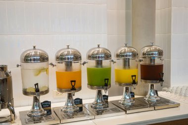 Açık büfede farklı meyve suları bulunan paslanmaz çelik içecek kutuları.