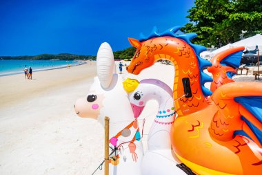 Rayong, Tayland - Nisan 01, 2025: Güzel, güneşli bir kumsalda, açık mavi gökyüzü ve arkaplanda turkuaz okyanus bulunan renkli şişme oyuncaklar Koh Samet, Rayong, Tayland