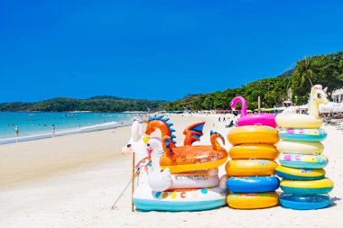 Rayong, Tayland - Nisan 01, 2025: Güzel, güneşli bir kumsalda, açık mavi gökyüzü ve arkaplanda turkuaz okyanus bulunan renkli şişme oyuncaklar Koh Samet, Rayong, Tayland