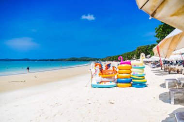 Rayong, Tayland - Nisan 01, 2025: Güzel, güneşli bir kumsalda, açık mavi gökyüzü ve arkaplanda turkuaz okyanus bulunan renkli şişme oyuncaklar Koh Samet, Rayong, Tayland