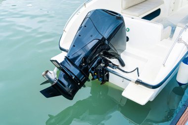 Sakin yeşil suda beyaz bir motorun arkasına bağlı modern siyah bir motorun yakın çekimi.