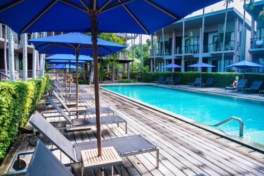 Rayong, Tayland - Nisan 01, 2025: Güneşli bir günde modern tatil köyleri ve yüksek palmiye ağaçları ile çevrili lüks açık yüzme havuzu