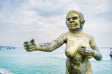 Rayong, Tayland - Nisan, 03, 2025: Bulutlu bir gökyüzünün altında deniz kenarında uzanan bir kolu olan efsanevi bir kadın heykelinin bronz heykeli