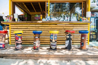 Rayong, Tayland - Nisan 01, 2025 Tiki temalı boyalı tabureler ve renkli dekorlarla dolu canlı bir sahil barı