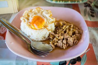 Tayland yemeği, kızarmış yumurta ve pirinçli domuz eti. Pembe tabak ve çatal bıçakla servis ediliyor.