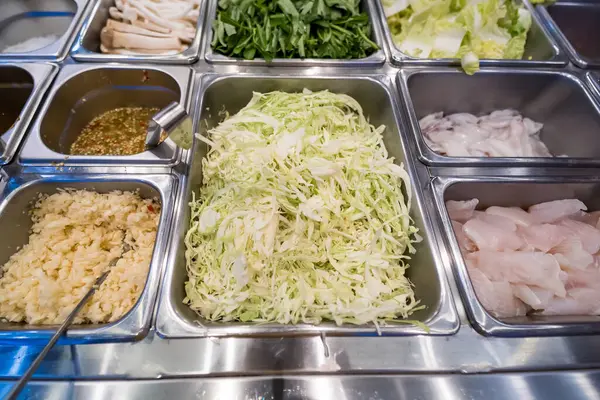 Açık büfe seçimi, doğranmış lahana, balık dilimleri, soslar ve paslanmaz çelik tepsilerde servis için taze sebzeler.