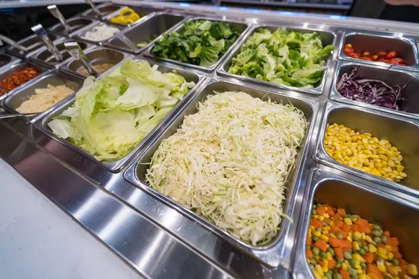 Açık büfe seçimi, doğranmış lahana, balık dilimleri, soslar ve paslanmaz çelik tepsilerde servis için taze sebzeler.