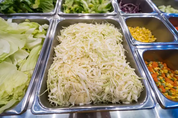Açık büfe seçimi, doğranmış lahana, balık dilimleri, soslar ve paslanmaz çelik tepsilerde servis için taze sebzeler.