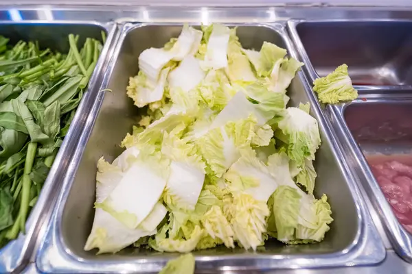 Salata barındaki paslanmaz çelik tepside taze kesilmiş Napa lahanasının yakın çekimi.