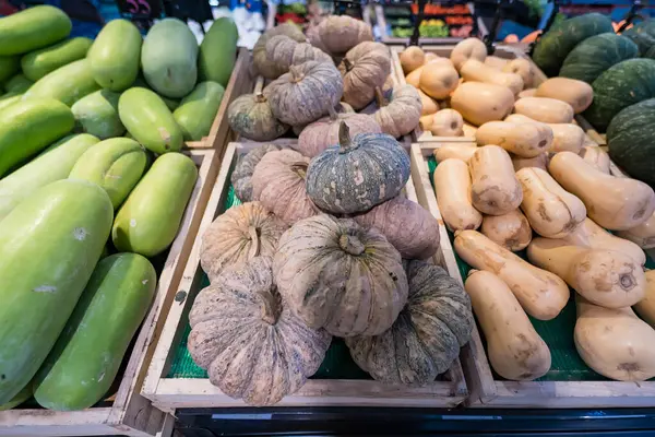 Canlı bir pazarda çeşitli mevsimlik ürünler sunan ahşap kasalarda çeşitli taze kabaklar ve su kabakları sergileniyordu.