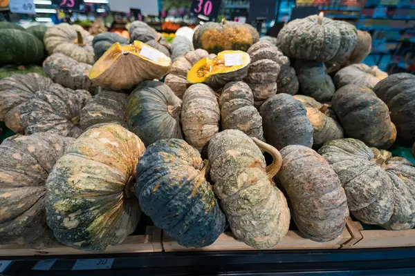 Görünür fiyat etiketleri ve canlı renkleriyle bir markette sergilenen çeşitli büyük balkabakları ve kabakları.