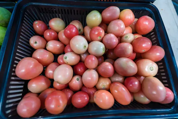 Bir market tezgahında sergilenen bir sepet olgun kırmızı domates. Satın alınmaya hazır taze ürünler sergileniyor.