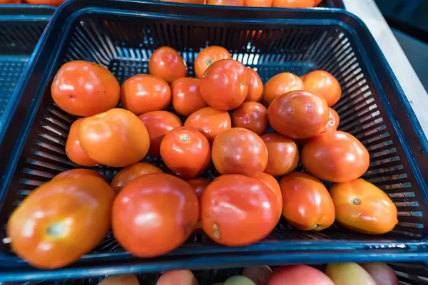 Bir market tezgahında sergilenen bir sepet olgun kırmızı domates. Satın alınmaya hazır taze ürünler sergileniyor.