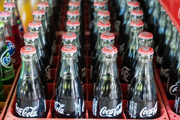 Bangkok, Tayland - 15 Mayıs 2025: Coca-Cola ve Fanta 'nın yer aldığı renkli cam soda şişeleri, düzgün bir içecek dağıtım ortamında düzenlenmiştir