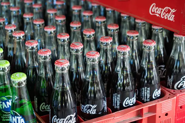 Bangkok, Tayland - 15 Mayıs 2025: Coca-Cola ve Fanta 'nın yer aldığı renkli cam soda şişeleri, düzgün bir içecek dağıtım ortamında düzenlenmiştir