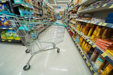 Bangkok, Tayland - 30 Mayıs 2025: Bangkok, Tayland 'da çeşitli paketlenmiş ürünler ve ev eşyalarıyla dolu bir market koridorunda bir alışveriş arabası.