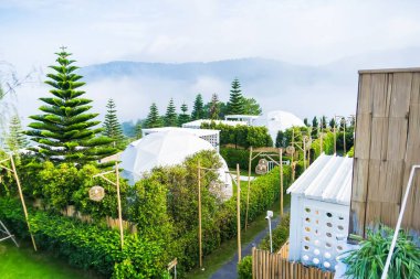 Phetchabun, Tayland - Haziran, 06, 2025: Tayland 'ın Phetchabun kentinde bulutların dağıtıldığı yemyeşil tepelerde kurulmuş ekolojik bir tatil beldesindeki modern jeodezik kubbelerin manzarası