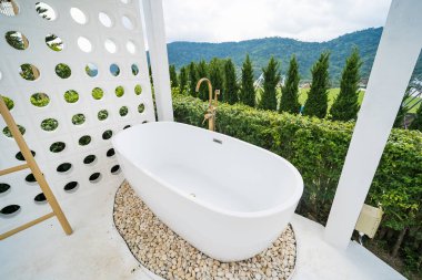 Phetchabun, Tayland - Haziran, 06, 2025: Bereketli yeşillik ve dağ manzaralı çakıl taşlarıyla çevrili açık hava serbest banyo küveti Phetchabun, Tayland