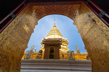 Chiang Mai, Tayland - 18 Temmuz 2025: Tayland 'ın Chiang Mai şehrinde geleneksel ve dingin bir ortamda açık mavi bir gökyüzünün altında karmaşık bir şekilde dekore edilmiş bir kemer kulesi.