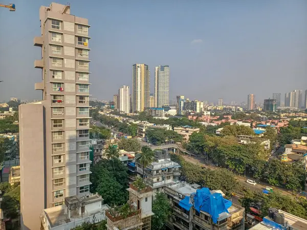 stock image Mumbai, India - 10 March 2024: Rural to urban development of mumbai in sion west with trees and skyscrapers in background