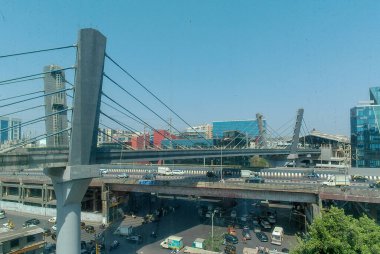 view of metro train leaving station 20-May 2024 Mumbai india, A Cable-stayed bridge on the roads beneath the bridge have little traffic with cars and bikes moving. clipart