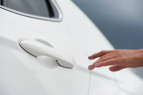 An adult woman opens the car door.