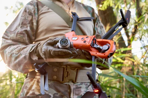 A Ukrainian military drone operator holds a broken quadcopter and a drone camera in his hands.