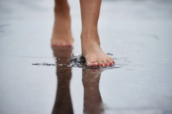 Women\'s feet walk through puddles.