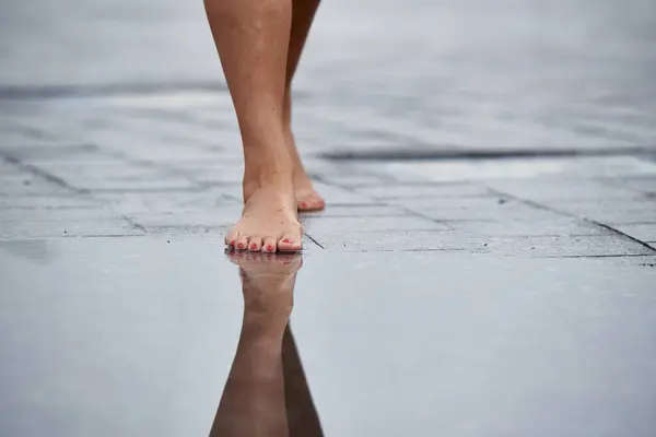 Women\'s feet walk through puddles.