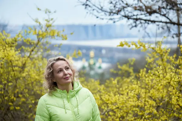 Adult woman, 50 years old, blonde. Portrait of a woman in a spring park.