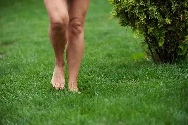 Adult woman walking barefoot on the grass in the park
