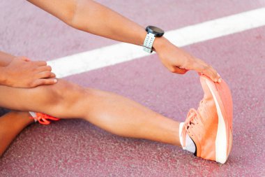 Atletizm pistinde, şehir sporu ve sağlıklı yaşam tarzında esneyen bir bayan sporcunun bacağının ayrıntıları
