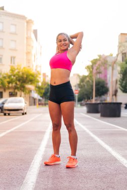 Gülümseyen sporcu kadın spor yaparken şehrin atletizm pistinde kollarını açıyor, şehir sporu ve sağlıklı yaşam tarzı kavramı, metin için kopyalama alanı