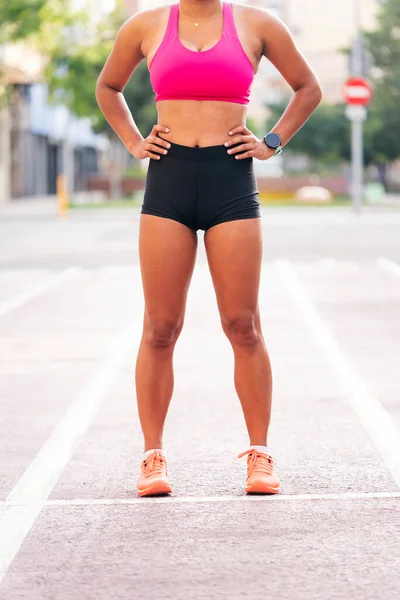 stock image body of an unrecognizable female athlete in running clothes standing on the city athletics track, urban sports and healthy lifestyle concept, copy space for text