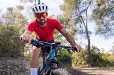 Genç bisikletçi dağ bisikletiyle ormanda sıkı bir şekilde antrenman yapıyor, doğada özgürlük ve spor kavramı, metin için yer kopyalıyor.