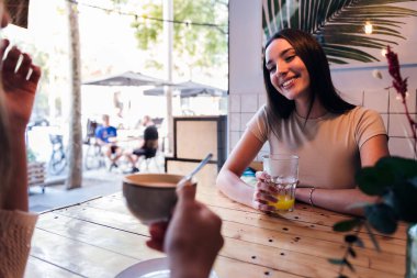 young caucasian woman smiling in love while drinking a juice during her date at a coffee shop, concept of friendship and love between women