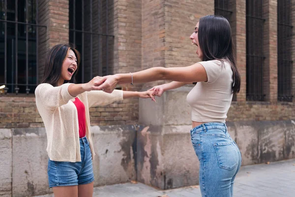 two young women holding hands full of joy during their date, concept of friendship and love between people of the same sex