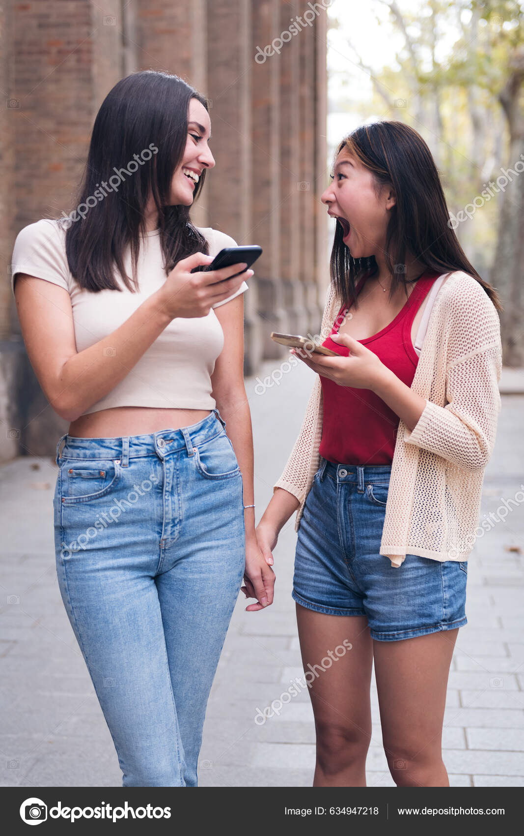 Two Young Women Sharing Confidences Having Fun Cell Phones While — Stockfotografi © raulmellado #634947218