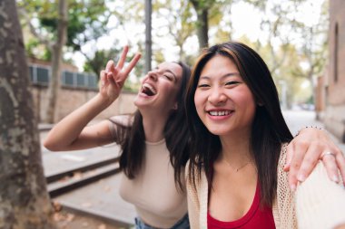 selfie of two young women laughing and having fun while dating, concept of friendship and love between people of the same sex