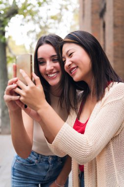 two young women smiling happy looking at content on a mobile phone, concept of technology of communication and social media