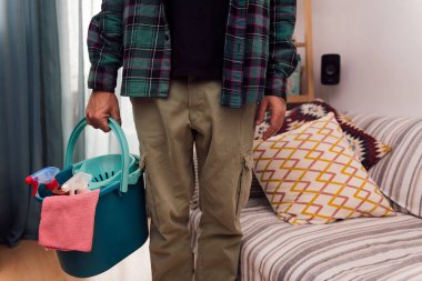 unrecognizable man holding a bucket with cleaning products and a rag, home cleaning concept